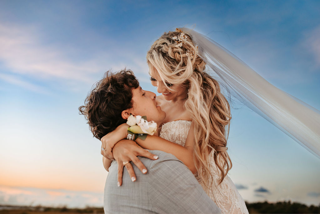 Bride and groom kissing at sunset, veil catching the breeze on Lido Beach