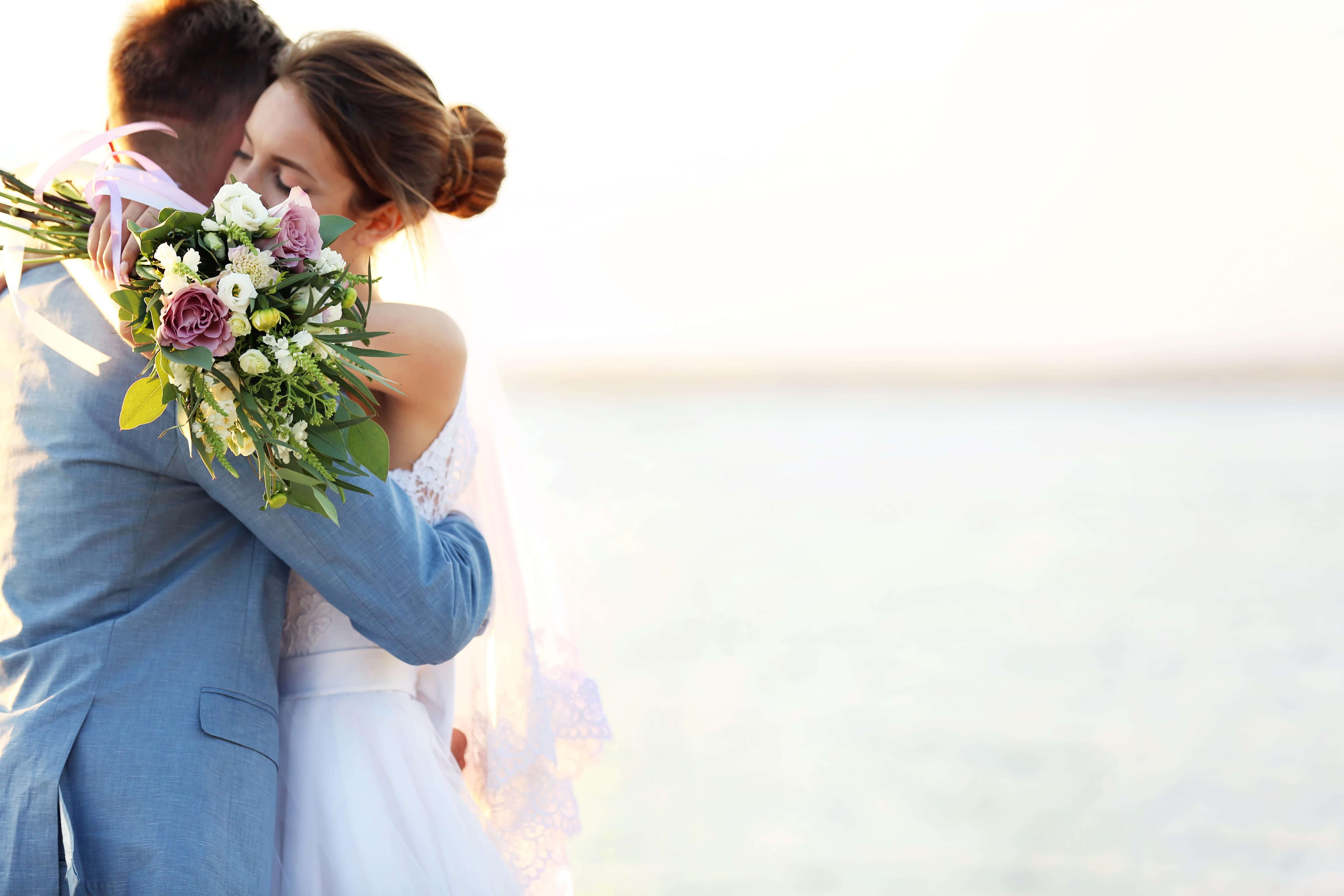 Couple embracing at sunset with a bouquet at Nokomis Beach